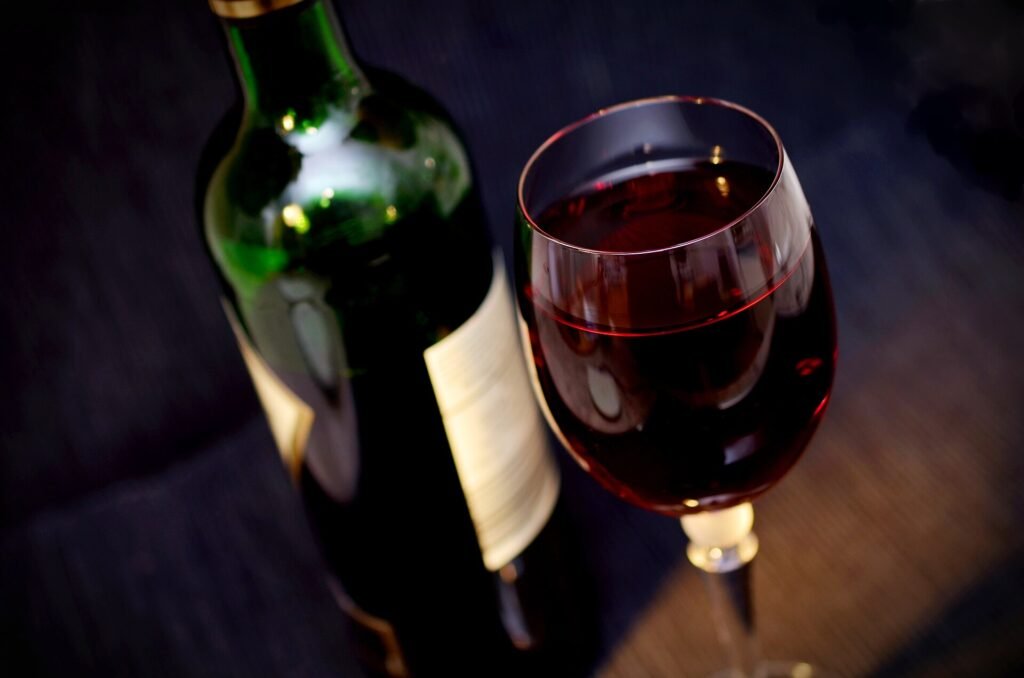 A bottle and a glass of red wine on a wooden table